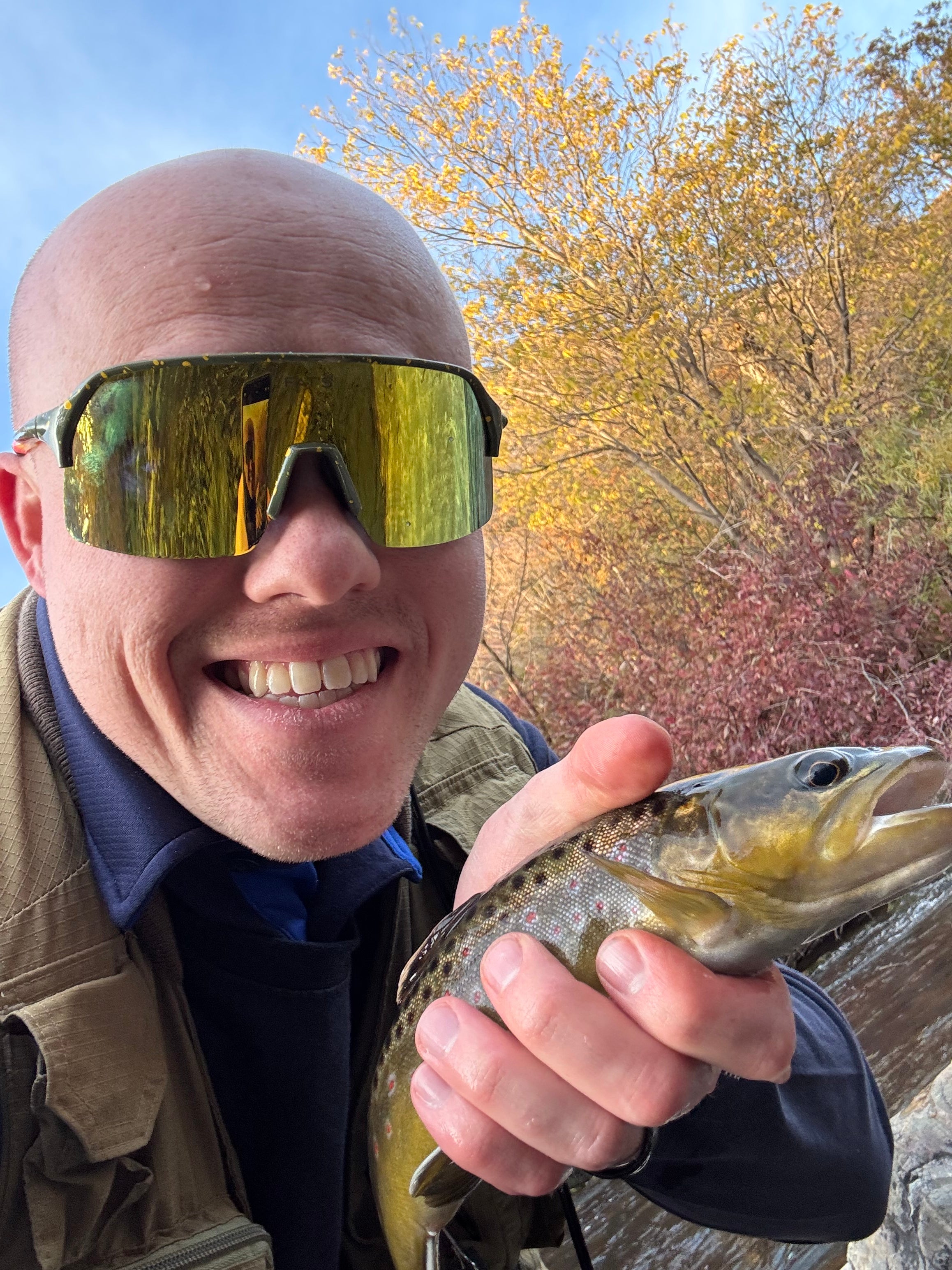 A man holding a fish wearing Fat's Brook Trout Sunglasses